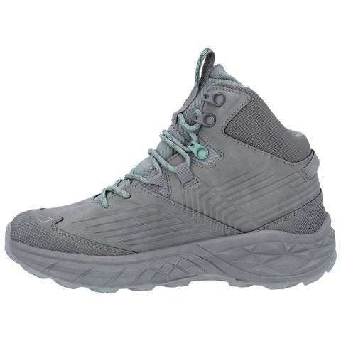 A gray athletic shoe stands upright showcasing a high-top design with textured surfaces and laces. Its color scheme features subtle teal accents against a muted backdrop.