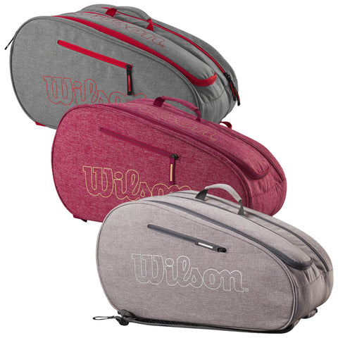 Three tennis bags in varying colors of gray and burgundy are displayed with zippers and carrying handles showing the brand name Wilson prominently on the side.