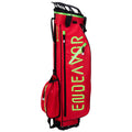 A bright red golf bag stands upright displaying large green lettering while featuring multiple compartments including a side pocket and a top handle for carrying.