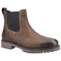 A brown leather Chelsea boot with a black elastic side panel rests on a flat surface showcasing its smooth finish and rugged sole indicating durability and casual style for versatile wear.