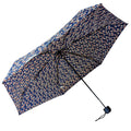 A floral-patterned umbrella is opened wide displaying a dark blue background with small colorful flowers while being held upright, suggesting protection from sun or rain.