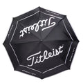 A black golf umbrella with white lettering opens wide providing coverage featuring the brand Titleist and the model Pro V1 creating a stylish protective canopy for players.