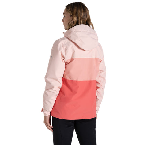 A person stands with their back facing the viewer wearing a color-blocked jacket featuring pink and coral hues in a casual setting. The environment is neutral and uncluttered.