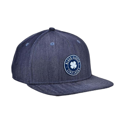 A dark blue baseball cap sits upright featuring a front patch with a clover design and the text BLACK CLOVER LIVE LUCKY surrounded by a circular border