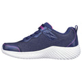 A blue athletic shoe with a textured fabric upper and white sole sits against a plain background featuring pink accents and a Velcro strap for closure.