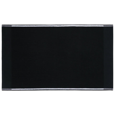 A rectangular black mat lies flat on a surface featuring textured lines and metallic borders along the top and bottom edges creating a modern aesthetic in a simple setting.