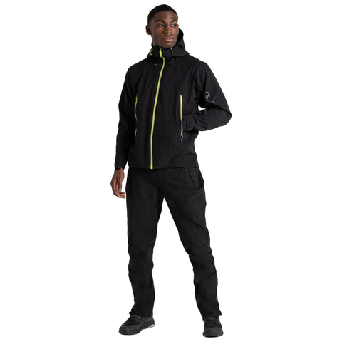 A person stands confidently wearing a black jacket with yellow zippers and black pants in a neutral background suggesting an outdoor or active context, ready for adventure.