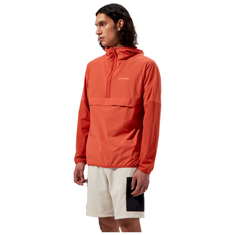 A young man wearing an orange hooded jacket stands sideways with a focused expression his left arm is slightly bent and he is wearing white shorts with black details against a plain white background