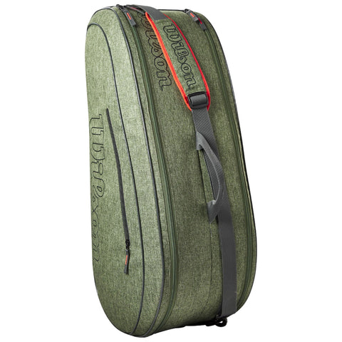 A green sports bag is standing upright with a shoulder strap and zipper. The surface has a textured fabric and the brand name is printed along the side in a prominent font.