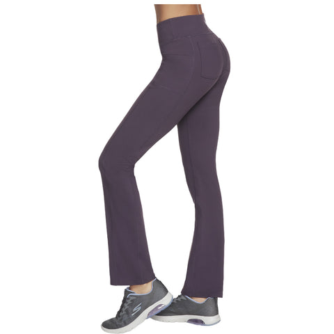 Purple flared workout pants are worn by a person standing profile wearing gray athletic shoes showcasing a form-fitting design with pockets in a neutral background.