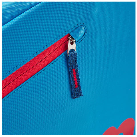 A blue fabric bag features a red zippered pocket highlighted by a silver zipper pull with a blue and red woven tab visible against a smooth backdrop.