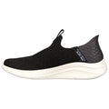 A black slip-on sneaker rests on a flat surface showcasing a textured knit upper with a flexible sole designed for comfort and ease of wear in casual settings.