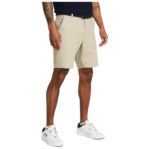 Beige shorts are worn by a man standing with one hand on his side and the other relaxed in front of him in a casual setting likely outdoors