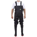 A person is wearing black waterproof waders with straps and red soles while standing upright. The background is plain, emphasizing the attire designed for wet environments.