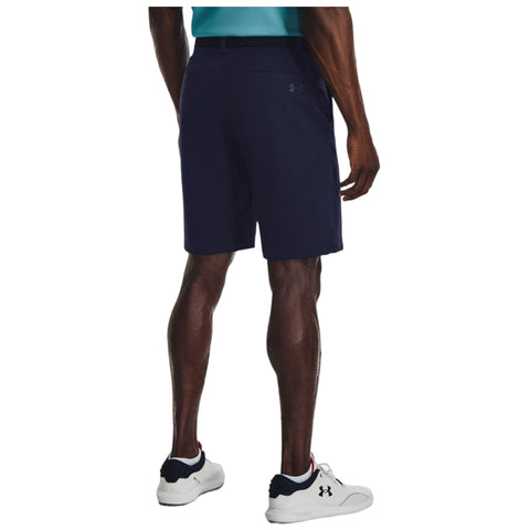 A person wears navy shorts and a teal shirt while standing on a surface. Their back is visible, revealing athletic sneakers and a confident posture.