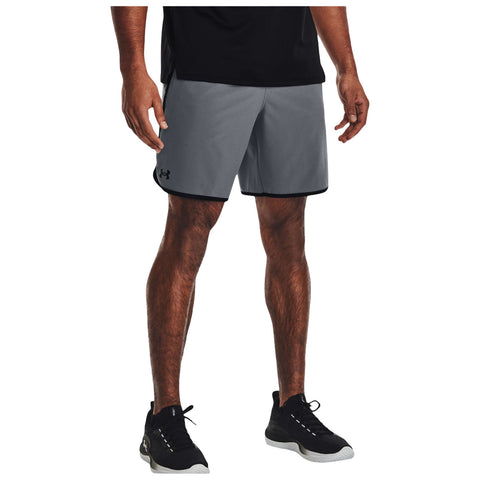 A person stands wearing gray athletic shorts and a black shirt with black athletic shoes. The setting seems casual and likely suited for exercise or outdoor activities.