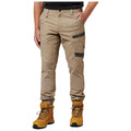 Beige work pants with black zippered pockets are worn by a standing person paired with yellow hiking boots in a neutral environment. The attire is practical and suitable for outdoor activities.