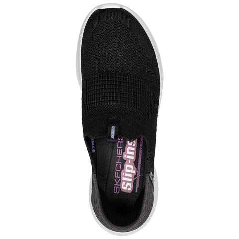 A black slip-on shoe is positioned with its top facing up revealing a textured surface and a cushioned lining the brand name Skechers is prominently displayed along with the term Slip-ins