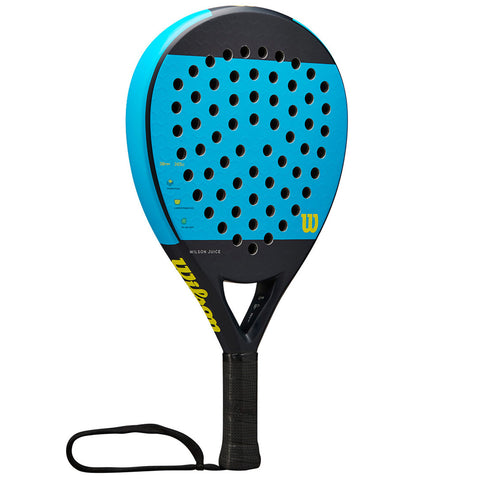 A blue and black paddle with a perforated surface is displayed upright. It features a textured grip handle and a wrist strap, designed for sports like padel or tennis. The brand name "Wilson" is visible.