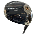 A golf driver is positioned diagonally with a shiny black and silver head featuring the name "PARADYM" and "FORGED CARBON" prominently displayed, set against an undefined background.