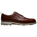 A brown leather golf shoe is shown positioned sideways with a sleek design and laces. The sole features small spikes for grip, suitable for use on the golf course.