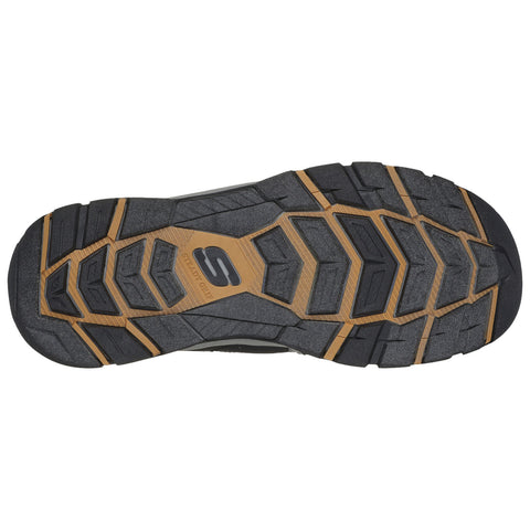 A shoe sole features a textured black rubber surface with a distinctive hexagonal pattern and a lighter brown middle section marked with an "S" logo indicating traction capability.