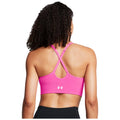 A person is wearing a bright pink sports bra with crisscross straps at the back in a plain white background highlighting the garment's design and vibrant color.