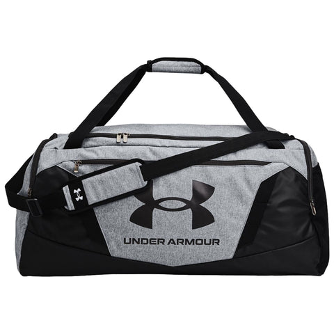 A gray and black duffel bag with a large Under Armour logo is lying flat with two straps and a detachable shoulder strap showcasing a sporty design suitable for athletic activities.