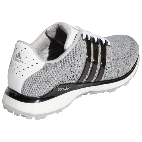 A grey athletic shoe with white and yellow accents displays a textured upper and a bright yellow outsole featuring a patterned grip design positioned vertically on a plain background.