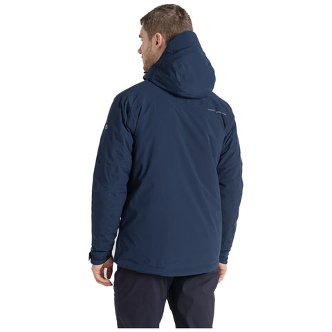 A person is standing with their back facing the viewer wearing a navy blue jacket with a hood in a plain, light background.