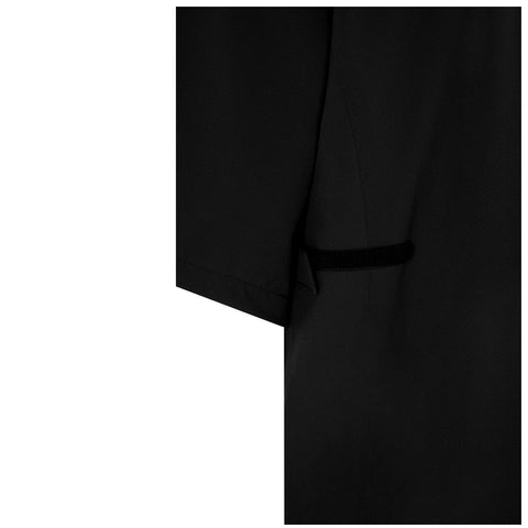 A piece of black fabric is partially visible hanging or draped revealing a sleeve with a pocket structure implying it might be part of a garment like a coat or blazer