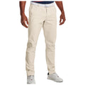 Light beige golf chinos are worn by a person standing upright with one hand on their hip in a casual outdoor setting, paired with a white belt and stylish athletic shoes for a sporty yet refined look.