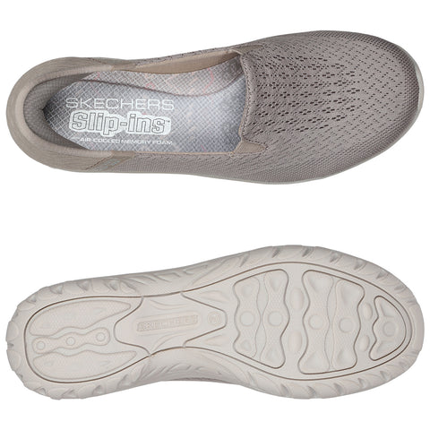 A grey slip-on shoe with a breathable mesh upper and a cushioned insole is positioned above a rubber outsole featuring a patterned tread in a neutral background.