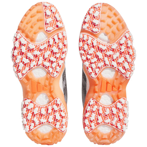 Shoe soles display a patterned rubber surface with vibrant orange and white elements designed for traction and grip on various terrains set against a plain white background.