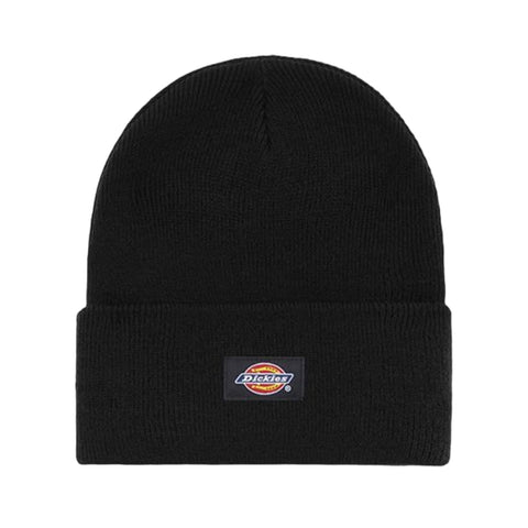 A black beanie hat lies flat with a folded cuff displaying a logo patch in the center featuring the word Dickies in a colorful design against a solid background