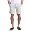 A person stands with hands in pockets wearing light gray shorts and black shoes in a casual setting suggesting a relaxed summer atmosphere.