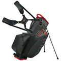 A golf bag with a sleek black design stands upright on its support legs featuring waterproof material and red accents displaying the model name Hybrido 4 with two padded shoulder straps attached.