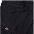 A black fabric garment features multiple pockets and detailing showcasing the Dickies brand logo prominently displayed on an upper patch. The texture appears durable and suited for workwear.