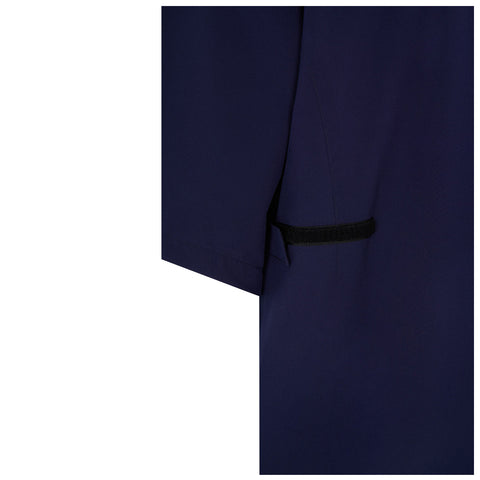 A navy blue garment hangs with a visible sleeve and an attached black fastening strap at the side, suggesting functionality and a structured design suitable for various settings.