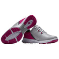 A pair of lightweight golf shoes features a sleek silver upper with pink accents and a textured sole designed for grip on the course showcasing a sporty and modern design.