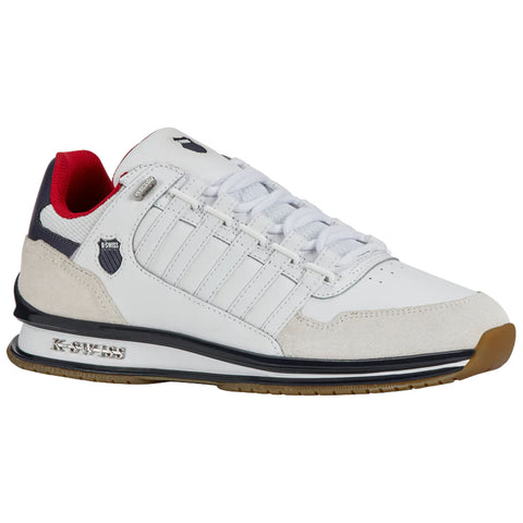 A white athletic shoe with red and navy accents is positioned at an angle highlighting its detailed stitching and textured suede near the heel designed for comfort and performance.