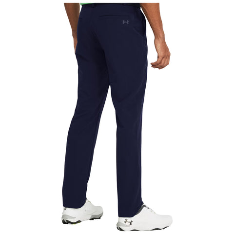 Navy pants are being worn by a person facing away with one hand resting at their side in a neutral setting featuring white athletic shoes designed for sports or outdoor activities.