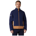 A man stands wearing a navy and brown jacket with a zipper and side pockets presenting a stylish design in a neutral background perfect for outdoor activities.