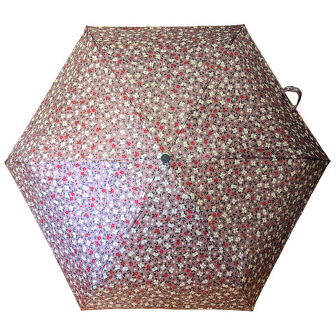 A floral-patterned umbrella is displayed open showcasing a light brown background adorned with small red and white flowers providing shade in an outdoor setting.