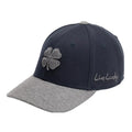 A navy blue baseball cap features a gray brim and a four-leaf clover emblem on the front with the text Live Lucky embroidered on the side.