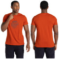 A man wears an orange t-shirt while adjusting it. The shirt features a graphic design on the front. He is in a neutral setting with no distinct background elements.