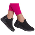 Black slip-on shoes are worn on a pair of legs dressed in bright pink leggings while the person stands or is in motion against a neutral background