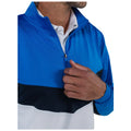 A person wearing a blue and white zip-up jacket is adjusting the zipper with one hand while their other hand rests on the jacket's front, set against a plain background.