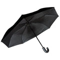 A black umbrella is opened with a curved handle displaying a smooth surface while casting a shadow against a light background suggesting protection from rain or sun in an outdoor setting.