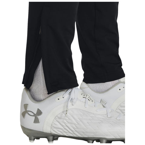 White cleats are positioned on a surface with black athletic pants partially unzipped at the ankles revealing white socks underneath indicating readiness for activity in a sporting context.